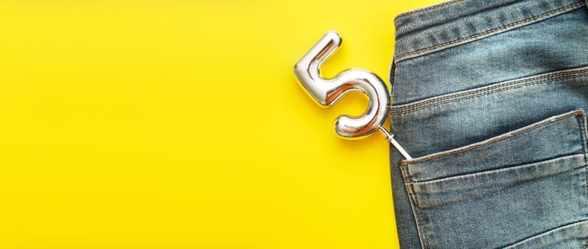 number 5 sticking out of the back pocket of blue jeans on yellow background photo
