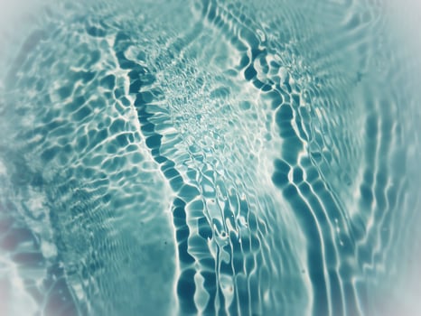 Defocus blurred transparent blue colored clear calm water surface texture with splashes and bubbles. Trendy abstract nature background. Water waves in sunlight with copy space. Blue watercolor shining photo
