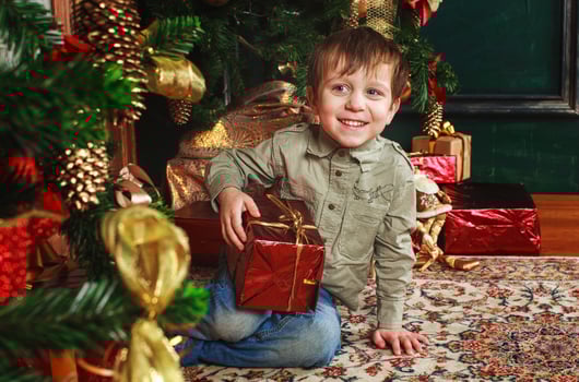 child boy sitting under the Christmas tree with gift box photo