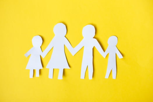Happy paper cut family holding hands on yellow background photo