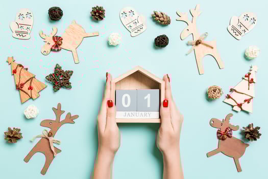Top view of female hands holding calendar on blue background. The first of January. Holiday decorations. New Year concept photo