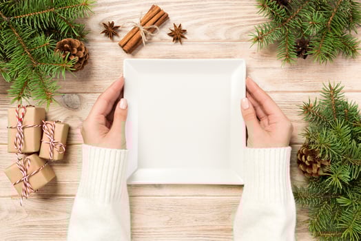 woman hand hold Top view. white square plate on a wooden table with christmas decoration. New Year concept photo