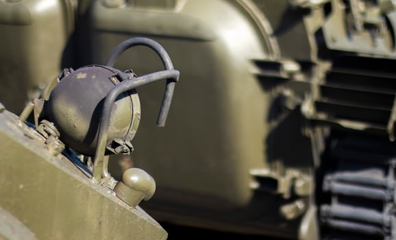 Front headlight with battle tank protection. Very bright searchlight on the tank turret, close-up. Armored infantry fighting vehicle. Fragment of an old armored personnel carrier, khaki headlight. photo