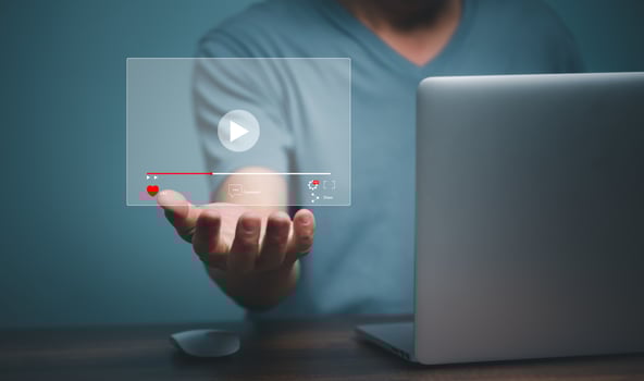Young man using laptop computer with hand holding virtual playing video streaming screen icon, future screen technology concept. photo