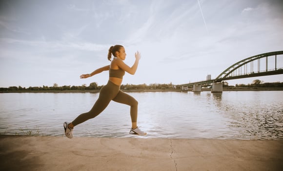 Active young beautiful woman running on the promenade along the riverside photo