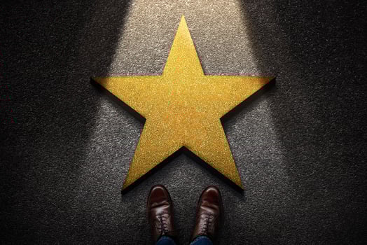 Success in Business or Personal Talent Concept. Top View of Business Person in Working Shoes Standing in front of a Golden Star. Light Shining on the Dark Cement Floor photo