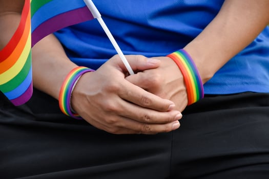 Rainbow flag holing in hand of asian gay which wears rainbow wristband to call out and shows LGBT gender diversity and respecting gender alternative around the world. photo