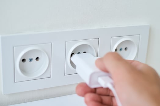 Male hand puts white plug in the socket photo