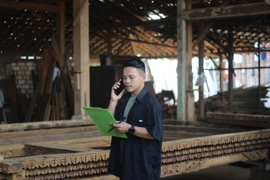 ASIAN YOUNG MAN BOSS OF WOOD COMPANY CALLING HER FRIEND AND CHECKING QUALITY photo