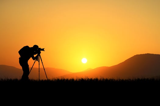Professional photographer taking pictures with camera and tripod in a beautiful meadow. photo