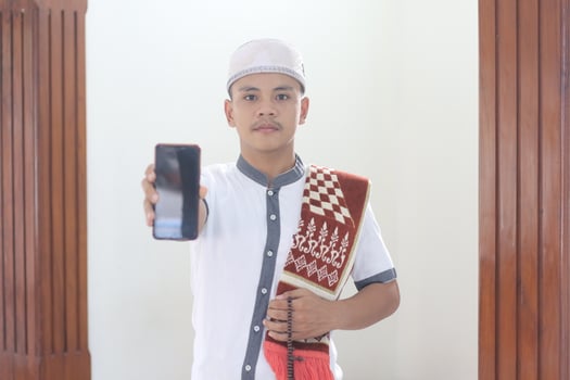 Young asian muslim praying in the mosque and calling her friend photo