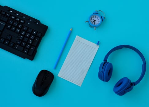 Flat lay home office desk. Workspace with laptop, headphones, pencil, alarm clock and a piece of paper for notes on blue background. Top view feminine background. photo