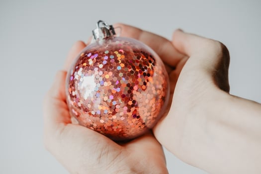 children's hands hold a red shiny New Year's ball, close-up. Family celebration concept for christmas and new year. photo