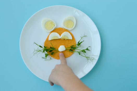 Easter breakfast bunny rabbit lunch plate, fun food art idea for kids of boiled egg, pancake and young greens. Top view. photo