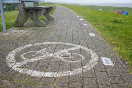 Stone footpath with a sign forbidding cycling painted on it, against the background of a bench. Security concept. photo
