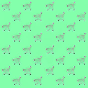 Shopping addiction, shopping lover or shopaholic concept. Many small empty shopping carts perform a pattern on a pastel colored paper background. Flat lay composition, top view photo