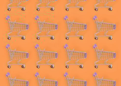 Shopping addiction, shopping lover or shopaholic concept. Many small empty shopping carts perform a pattern on a pastel colored paper background. Flat lay composition, top view photo