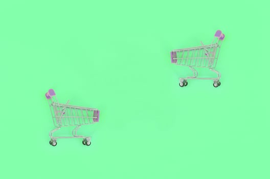 Shopping addiction, shopping lover or shopaholic concept. Small empty shopping cart lies on a pastel colored paper background. Flat lay minimal composition, top view photo