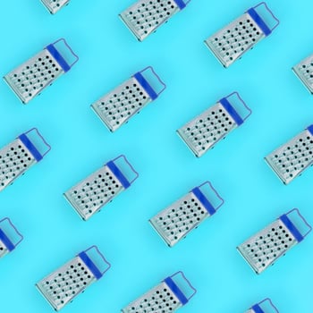 Small stainless steel graters lies on a pastel colored paper. Kitchen accessories. Tools for cooking. Flat lay top view photo
