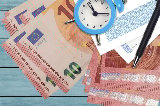 10 euro bills and alarm clock with pen and envelopes. Tax season concept, payment deadline for credit or loan. Financial operations using postal service photo