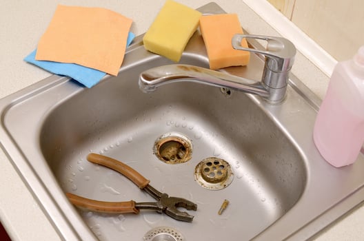 Pliers inside the silvery kitchen sink with a disassembled protective filter photo