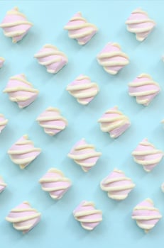 Colorful marshmallow laid out on blue paper background. pastel creative textured pattern. minimal photo