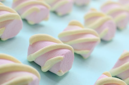 Colorful marshmallow laid out on blue paper background. pastel creative textured pattern. Perspective macro shot photo