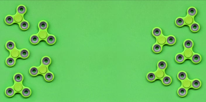 Many green fidget spinners lies on texture background of fashion pastel green color paper in minimal concept photo