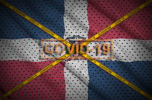 Dominican Republic flag and Covid-19 stamp with orange quarantine border tape cross. Coronavirus or 2019-nCov virus concept photo