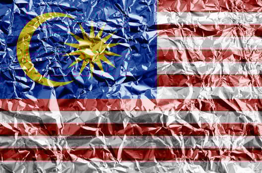 Malaysia flag depicted in paint colors on shiny crumpled aluminium foil closeup. Textured banner on rough background photo