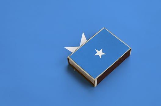 Somalia flag is pictured on a matchbox that lies on a large flag photo
