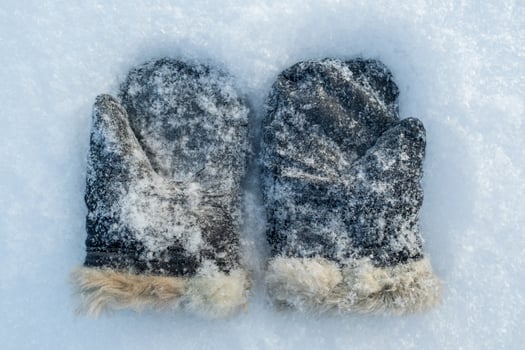 Snow-covered retro mittens, suede with natural fur on the snow, on a frosty winter day. Top view. photo