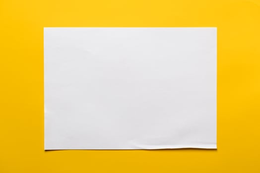 Frame of a sheet of white paper on a yellow background. Copy space. Top view. photo