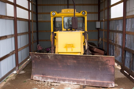 Large wheeled tractor with a dozer blade for clearing roads from snow. Yellow wheel loader in the garage. photo