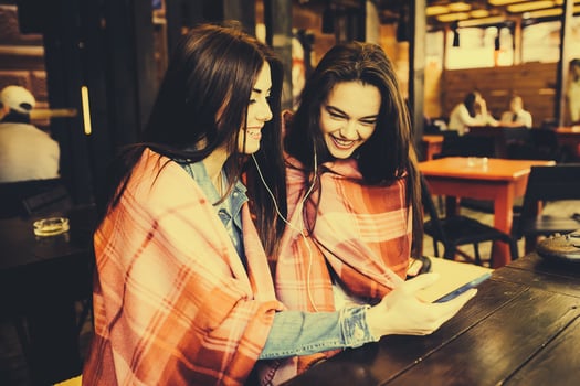 Two girl sitting listening to music with a smartphone photo