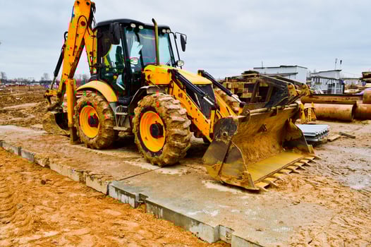 Big bright yellow powerful industrial heavy excavator tractor, bulldozer, specialized construction equipment for road repair during the construction of a new micro-district in a big city photo