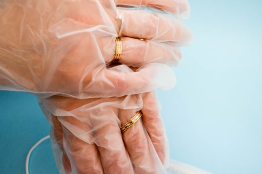 Gold wedding rings on hands in protective medical rubber disposable gloves for protection against dangerous deadly diseases of microbes and viruses by coronavirus covid-19 on a blue background photo
