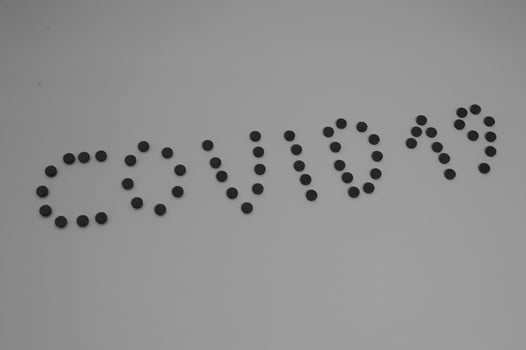 Black and white Kovid -19 inscription made of round yellow medical pharmaceutical tablets from coronavirus for the treatment of pandemic diseases and viruses. The background photo