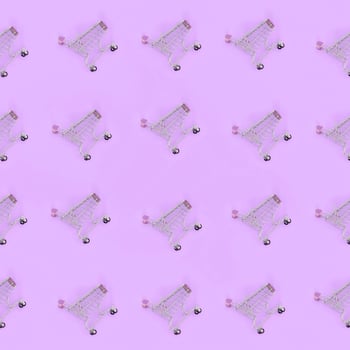 Shopping addiction, shopping lover or shopaholic concept. Many small empty shopping carts perform a pattern on a pastel colored paper background. Flat lay composition, top view photo