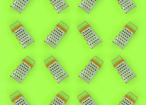 Small stainless steel graters lies on a pastel colored paper. Kitchen accessories. Tools for cooking. Flat lay top view photo