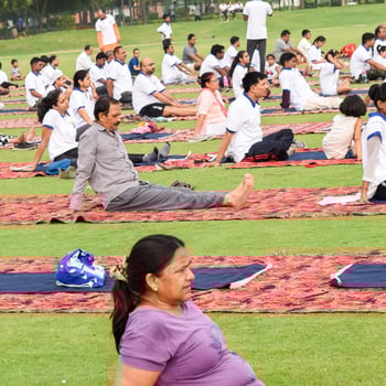 New Delhi, India, June 21 2022 - Group Yoga exercise session for people at Yamuna Sports Complex in Delhi on International Yoga Day, Big group of adults attending yoga class in cricket stadium photo