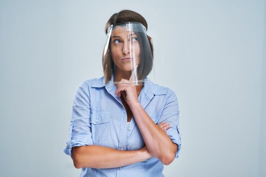 Attractive woman wearing protective shield thinking over white background photo