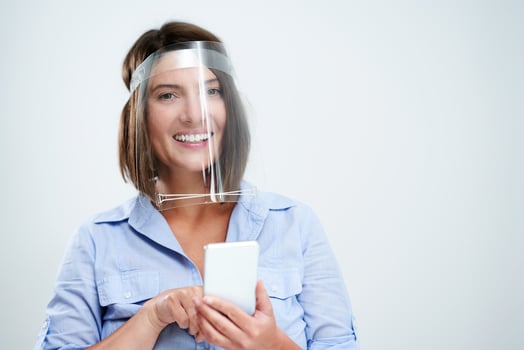Woman wearing protective mask holding smartphone over white background photo