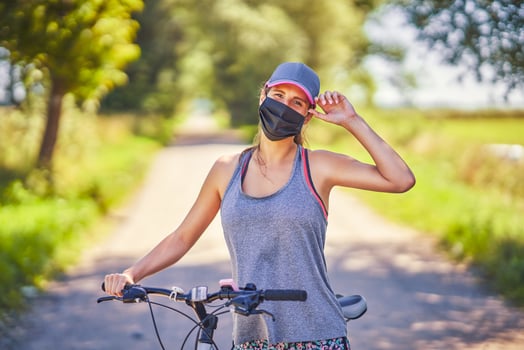 Young woman on a bike in countryside wearing a mask photo