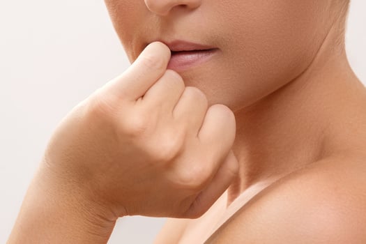 Closeup of a female mouth biting her fingers photo
