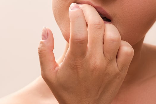 Closeup of a female mouth biting her fingers photo
