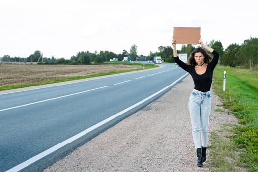 Hitchhiker on the road is holding a blank cardboard sign photo