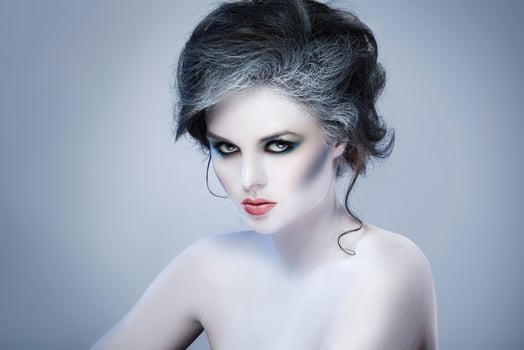 Woman in white body-art in creative image of winter, snow queen, or another sad or evil character photo