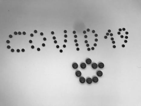 Black and white Kovid -19 inscription made of round yellow medical pharmaceutical tablets from coronavirus for the treatment of pandemic diseases and viruses. The background photo
