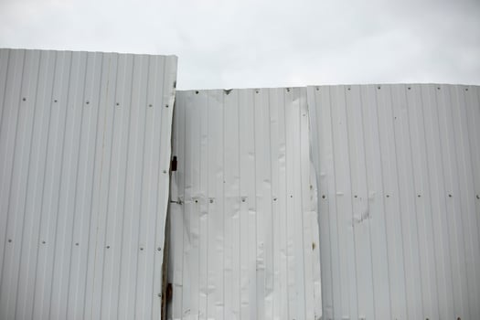 Broken steel profile fence. Wrinkled metal fence. White steel barrier. photo